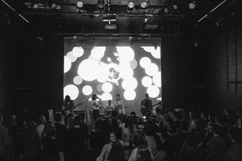 Black and white, shot from the back of the room over the crowd